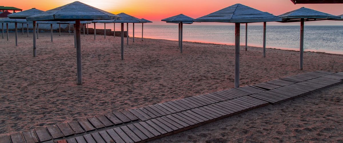 A couple of lawn chairs sitting on top of a sandy beach